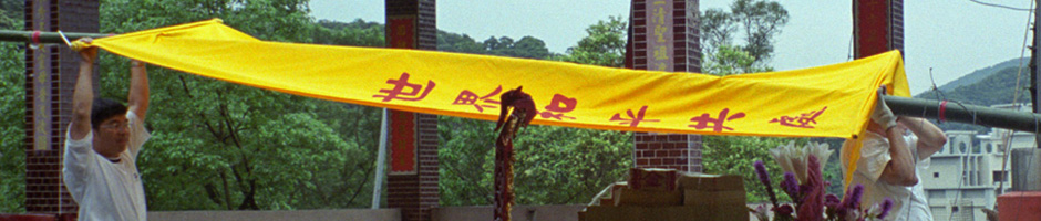 A photograph of two men moving large yellow banner with red writing on it on a large pole used to for Taiwan Photogallery Set J